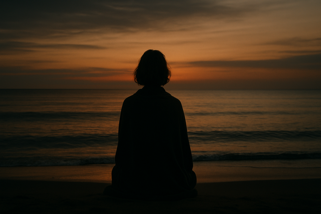 A solitary figure standing on a quiet shoreline at dusk, symbolizing completion, release, and compassionate inner wisdom.